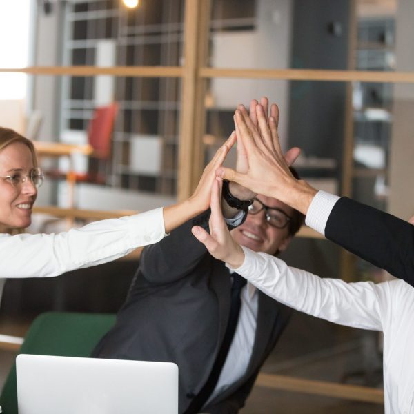 Happy business team giving high-five together promising engageme Happy business team giving high five promising engagement and loyalty, partners group joining hands as concept of common victory celebration, corporate success, good relations, unity or togetherness